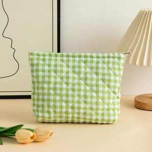 Detailed close-up of green checkered quilted cosmetic bag with metal zipper and soft fabric