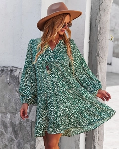 Detail of green polka dot dress featuring a V-neck and ruffled hemline in daylight