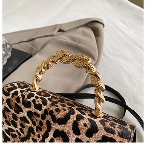 Detailed view of leopard print crossbody bag with ornate gold snake-shaped metal handle
