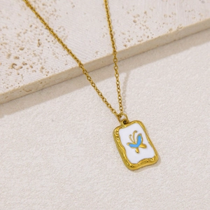Elegant gold butterfly pendant necklace with blue enamel on a textured stone surface