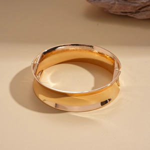 Macro detail of high-polish gold wide-band hinged cuff with smooth mirror finish
