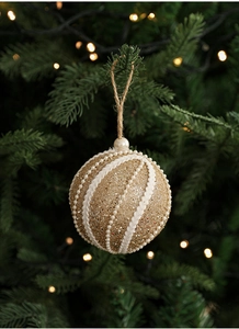 Close-up of champagne gold glitter Christmas ball with pearls and spiral cord on a tree