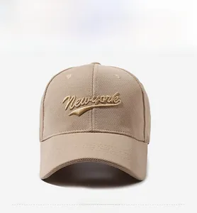 Detailed view of 3D gold New York embroidery on a beige textured cotton baseball cap
