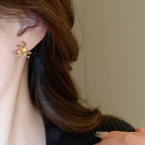 Macro shot of minimalist gold irregular flower earrings worn on the earlobe