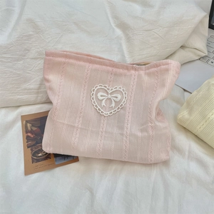 Detail of pink striped cosmetic bag featuring white lace heart and bow pattern