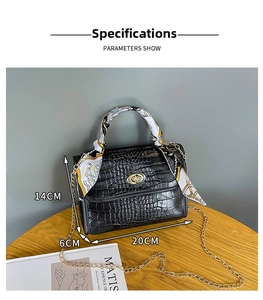 Detail shot of black crocodile texture bag with silk scarf handle and gold twist lock