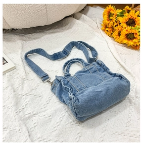 Close-up of blue denim tote bag with adjustable strap and decorative floral background