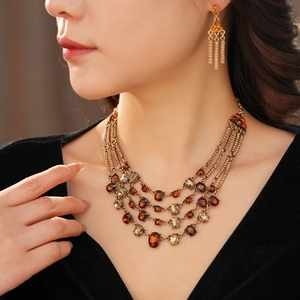 Detail of vintage layered gold necklace and matching amber stone earrings on a model