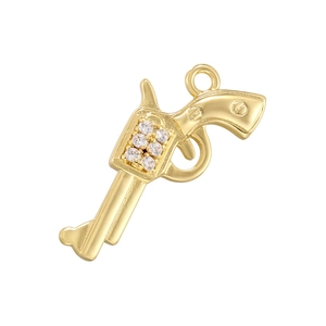 Western cowboy style gold revolver pendant with crystal accents on a white background