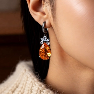Close-up of vintage orange teardrop pendant earrings with zircon flower on female model