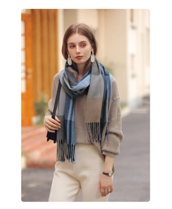 Blue and brown plaid scarf with tassels worn by model in a street style setting