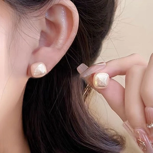 Close-up of elegant square pearl stud earrings with champagne luster on a model