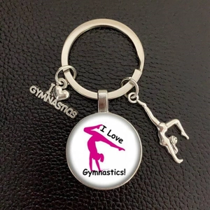 Detail of silver I Love Gymnastics keychain with heart charms on black leather texture