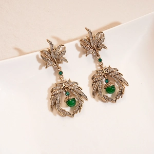 Detailed macro view of vintage bronze leaf earrings with crystals and green beads