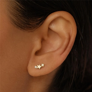 Detail of gold star and moon stud earring with diamonds and pearls on model ear