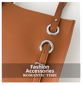 Macro view of textured brown leather bag featuring large silver metal eyelets and stitching