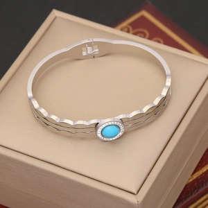 Detail of silver wavy open bangle with center blue stone and zircon halo on jewelry box