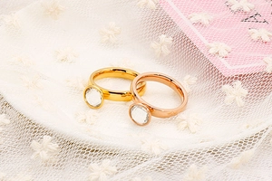 Dettaglio di anelli in acciaio oro e rosa con grandi pietre di zircone tondo lucido