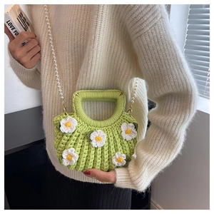Detail of green handmade woven shell bag with daisy flowers and pearl strap