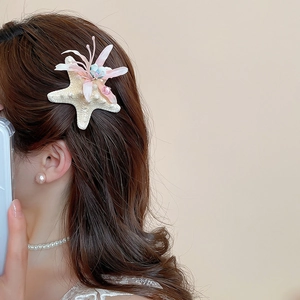 Detail of starfish hair clip with pink fabric flowers and pearl on female model