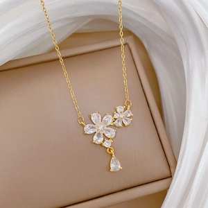 Elegant gold titanium steel necklace with zircon flower pendant on beige silk box