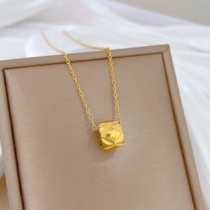 Macro shot of gold cylinder pendant with diamond pattern on brown display board