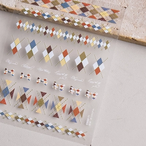 Detailed close-up of colorful argyle and bow nail art stickers on a stone surface