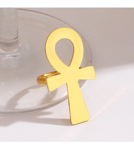 Detailed view of a gold-plated Egyptian Ankh cross ring leaning against a clear glass stem