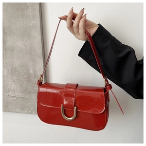 Close-up of shiny red patent leather texture and gold horseshoe magnetic buckle detail