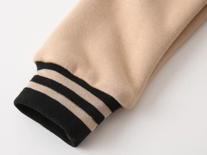 Detail of striped elastic ribbed cuffs on a beige boys' fleece baseball jacket