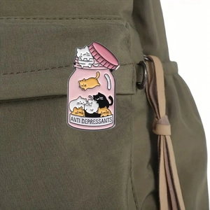 Cute enamel cat jar pin with 'Anti Depressants' text on a green canvas backpack