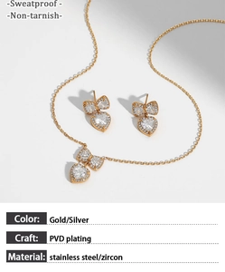 Detail of gold bow heart jewelry set with zircon stones on a light grey background