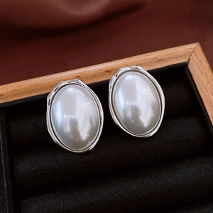 Close-up of vintage oval pearl earrings with irregular silver metal frames on tray