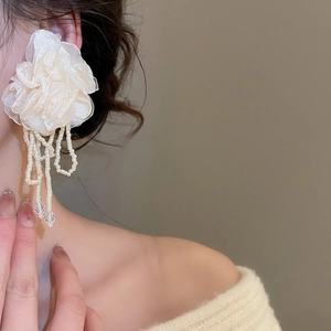 Close-up of elegant chiffon flower earrings with long white beaded tassels and crystals