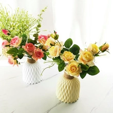 Detailed view of pink and yellow artificial roses in textured vases with twine bows