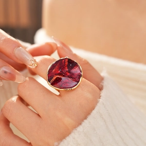 Close-up of a model wearing a gold ring with deep red enamel and irregular texture