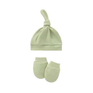 Close-up of soft light green cotton knit newborn knotted hat and anti-scratch mittens set