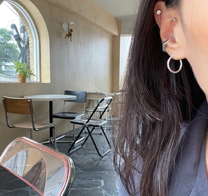Close-up of polished 925 silver minimalist hoop earring and geometric ear cuff on model