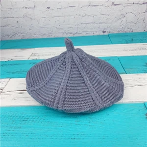 Detail shot of the coarse knit texture and striped pattern of a dark grey knitted beret