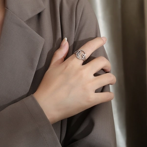 Detail shot of a silver hollow heart ring with abstract figures on a model hand