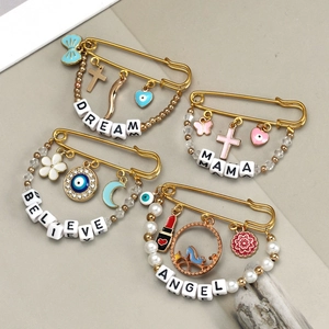 Detail view of four gold-tone safety pin brooches with evil eye charms and letter beads
