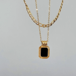 Detail of vintage double-layer gold necklace featuring a black square pendant and Figaro chain