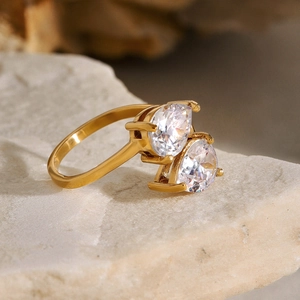 Macro shot of gold double pear-cut cubic zirconia ring on natural stone background