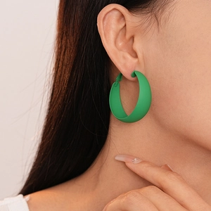 Detail of large matte green C-shaped hoop earring worn on ear with premium spray finish