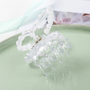 Détail de pince à cheveux papillon transparente avec perles sur un fond vert doux