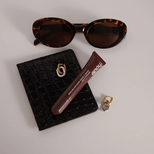 Close-up of interlocked gold and silver oval hoop earrings on a black leather card holder