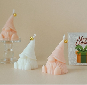 Detail shot of cute Christmas gnome candles in pink and white with golden bells