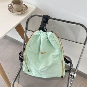 Detailaufnahme des minzgrünen Kordelzug-Rucksacks mit Zakka-Stickerei auf klarem Stuhl