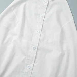 Close-up of white cotton shirt dress featuring a neat single-breasted button placket detail