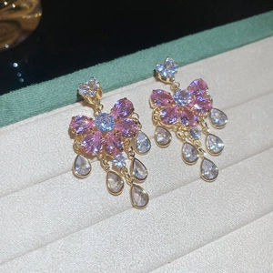 Detail of pink bow earrings with sparkling zircon tassels and elegant gold setting